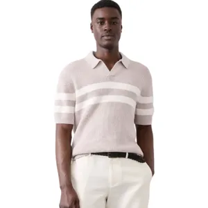 A man is wearing a light-colored, short-sleeve knit polo with white horizontal stripes, paired with light beige shorts and a black belt.