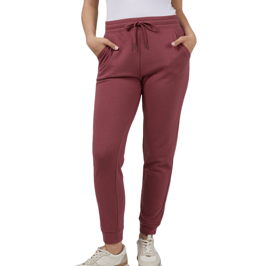 The 32 Degrees Comfort Tech Joggers are maroon with a tapered leg design, featuring an adjustable drawstring waistband and side pockets. They offer a casual look paired with white sneakers.