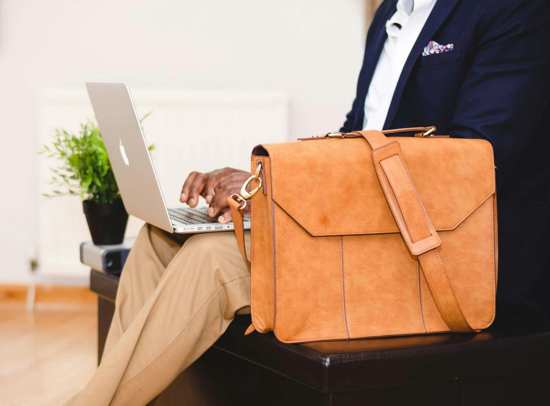 A laptop and a brown leather briefcase are featured.