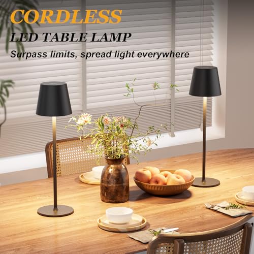 Cordless LED table lamp with a sleek black design, placed on a dining table alongside a bowl of fruit and a vase with flowers.