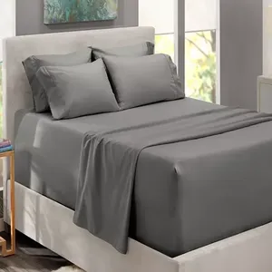 A neatly made bed with gray sheets, including pillowcases, a fitted sheet, and a flat sheet, against a neutral-colored headboard.