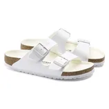 White two-strap sandals with adjustable buckles, featuring a cork footbed and white soles.