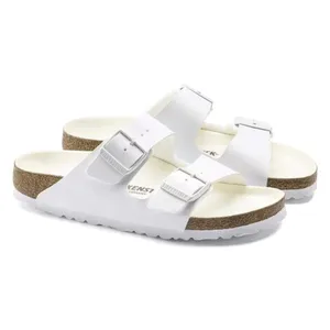 White two-strap sandals with adjustable buckles, featuring a cork footbed and white soles.