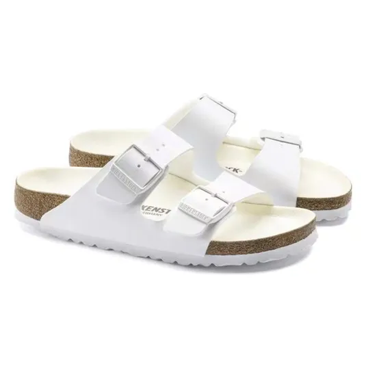 White two-strap sandals with adjustable buckles, featuring a cork footbed and white soles.