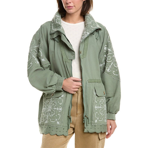 A woman wears a light green jacket with floral embroidery and a scalloped hem, paired with beige pants.