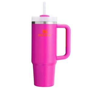 A pink Stanley insulated tumbler with a handle and straw, featuring a logo on its side.