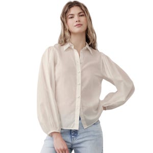 A cream-colored Banana Republic puff sleeve shirt with long sleeves, button-down front, and soft fabric, paired with light blue jeans.