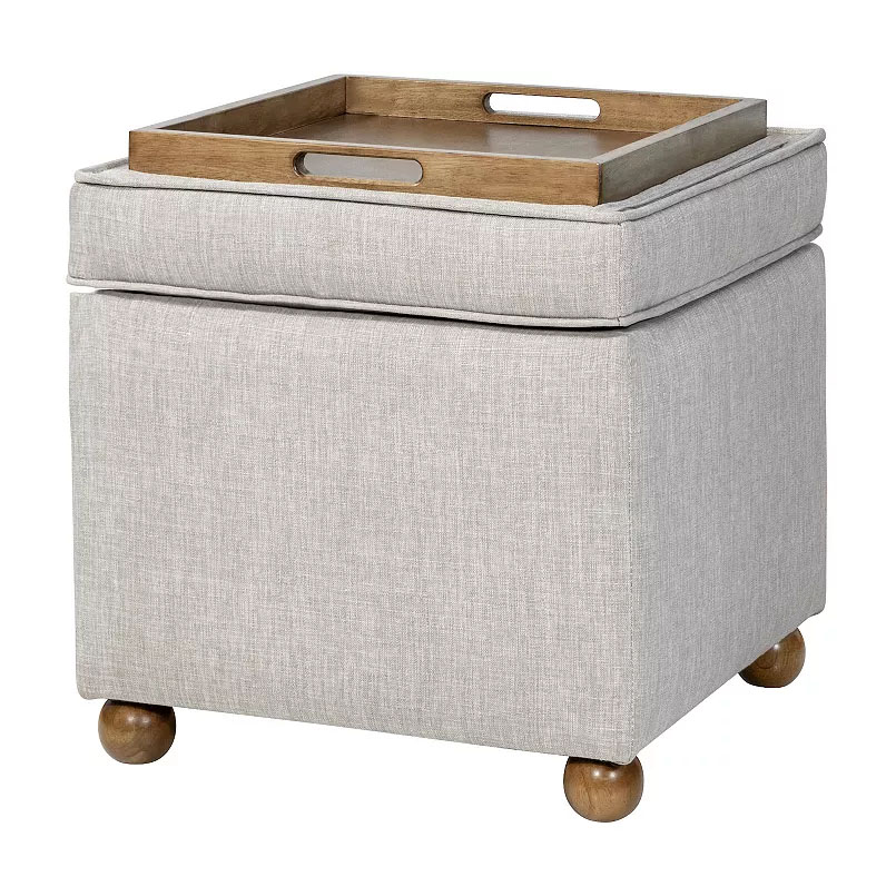 A light gray storage ottoman stands on wooden bun feet and features a cushioned lid that flips to reveal a wooden serving tray.