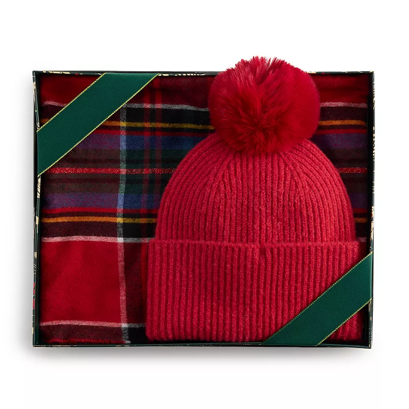 A Nine West Beanie & Scarf Set featuring a red ribbed beanie with a pom-pom and a matching plaid scarf in red, blue, and orange tones, presented in a gift box with green ribbon accents.