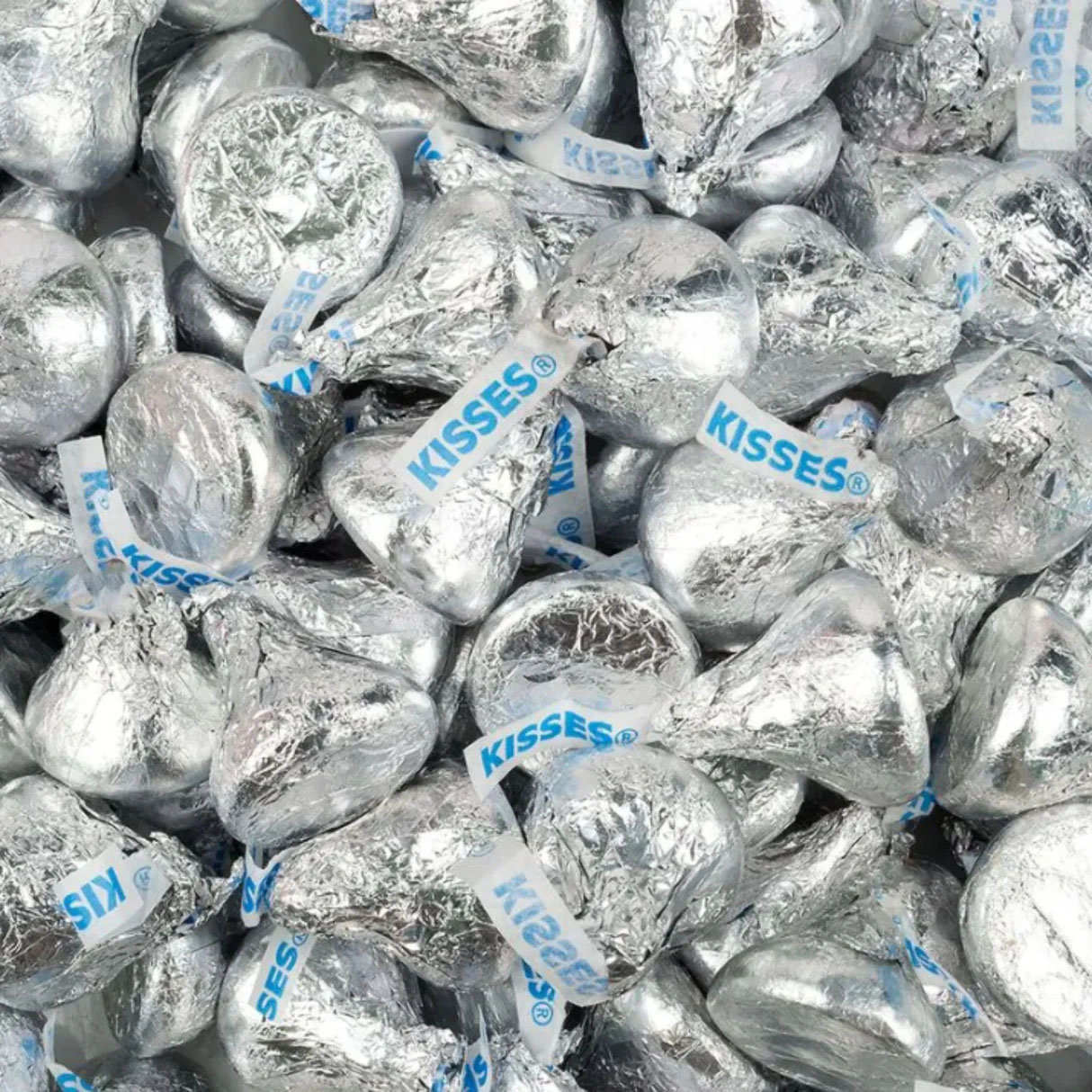 5lbs of Hershey's Kisses, wrapped in silver foil with a distinctive paper plume labeled \“KISSES,\“ scattered in a pile.