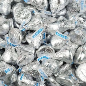 5lbs of Hershey's Kisses, wrapped in silver foil with a distinctive paper plume labeled \“KISSES,\“ scattered in a pile.