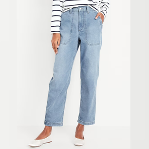 A person is wearing light blue jeans and white pointed-toe flats, paired with a striped long-sleeve shirt.