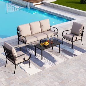 A four-piece patio set including a three-seater sofa with beige cushions, two matching armchairs, and a rectangular coffee table, arranged on a patterned outdoor rug by a pool.