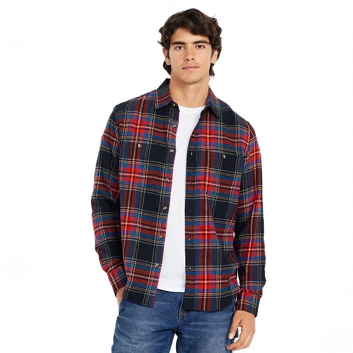 A man wears a plaid flannel shirt featuring a blend of red, blue, and yellow colors, with a collar, front pockets, and button closures. He's also in a white tee and blue jeans.