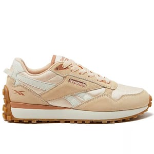 A beige and white Reebok sneaker featuring suede overlays, mesh accents, and a gum sole, designed for casual wear.