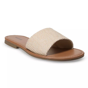 A beige woven slide sandal with a flat brown sole and an open toe design.