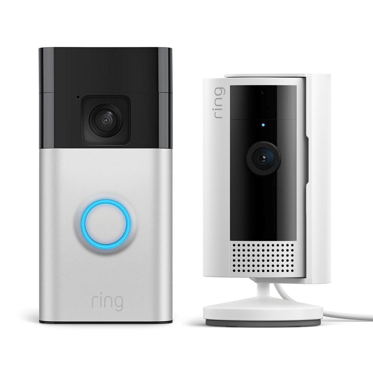 A Ring Doorbell with a blue-lit button beside a Ring Indoor Camera on a stand, both featuring cameras for home security.