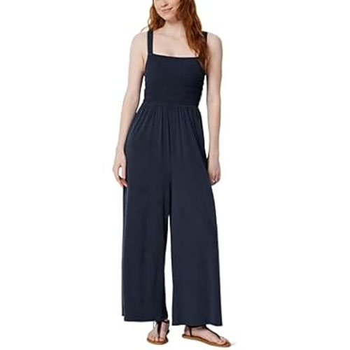 A woman is wearing a navy blue sleeveless jumpsuit with wide legs, paired with flat sandals.
