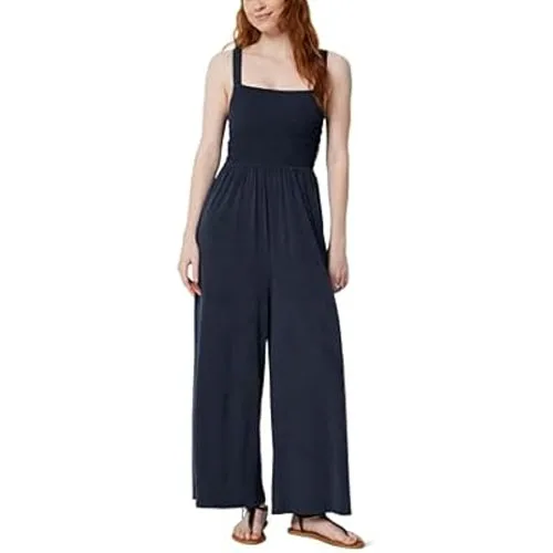 A woman is wearing a navy blue sleeveless jumpsuit with wide legs, paired with flat sandals.