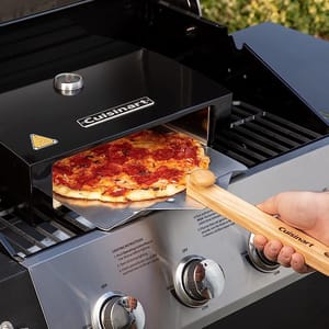 A Cuisinart pizza oven with a pizza being removed using a wooden pizza peel.