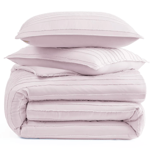 A stack of light pink, pleated bedding items, including two pillows and a folded comforter.