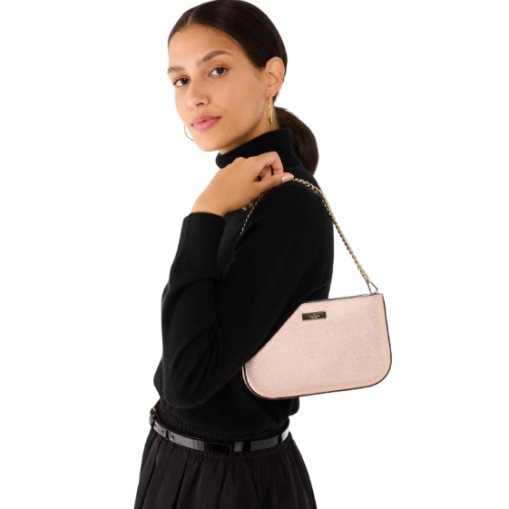 The Kate Spade Pochette is a small, elegant bag with a light pink finish and a sleek gold chain strap, ideal for carrying essentials. It features a simple, chic design suitable for both casual and formal occasions.