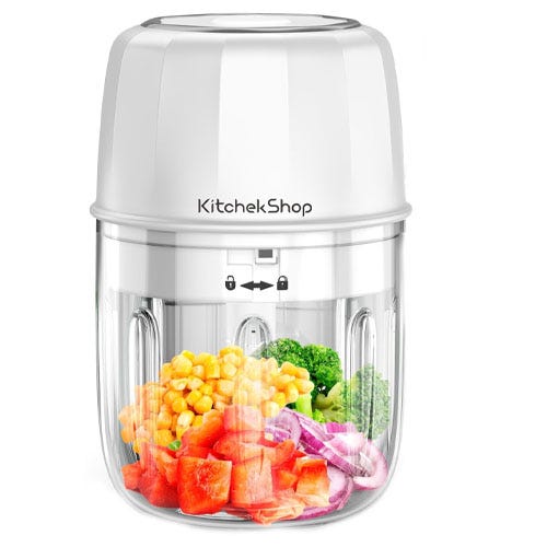A small electric food processor with various vegetables.