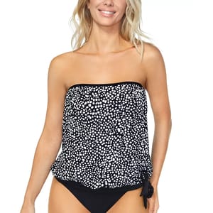 A woman is wearing a strapless, polka-dotted tankini top with a tie detail on the side, paired with black bikini bottoms.