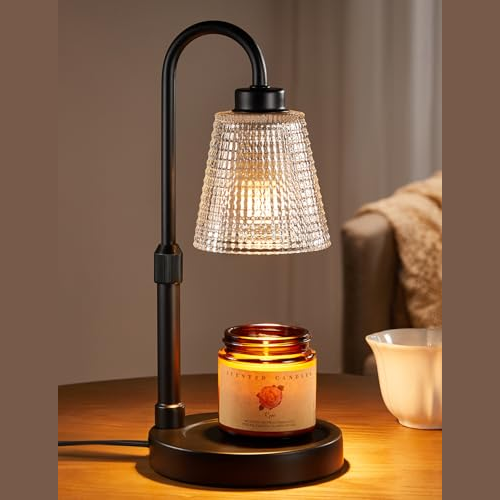 A black electric candle warmer lamp with a textured glass shade sits on a table, heating an amber jar candle labeled \“Love Petal Candle.\“