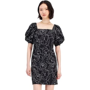 A woman is wearing a black shift dress with puff sleeves and white floral embroidery.
