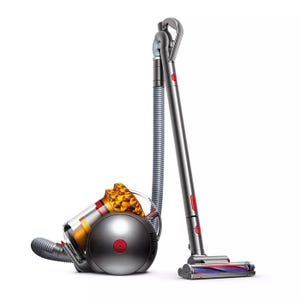 Dyson Big Ball Turbinehead Vacuum is a cylindrical vacuum cleaner with a grey and orange design, featuring a ball mechanism for easy maneuverability and a turbine head for efficient cleaning on various surfaces.