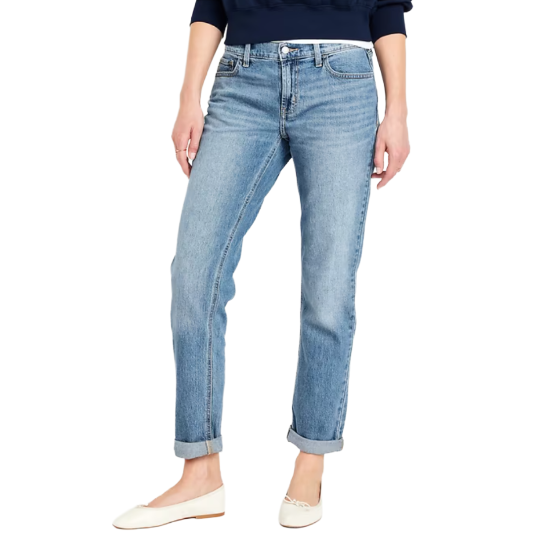 A person is wearing light blue, cuffed straight-leg jeans paired with a dark top and white flats.