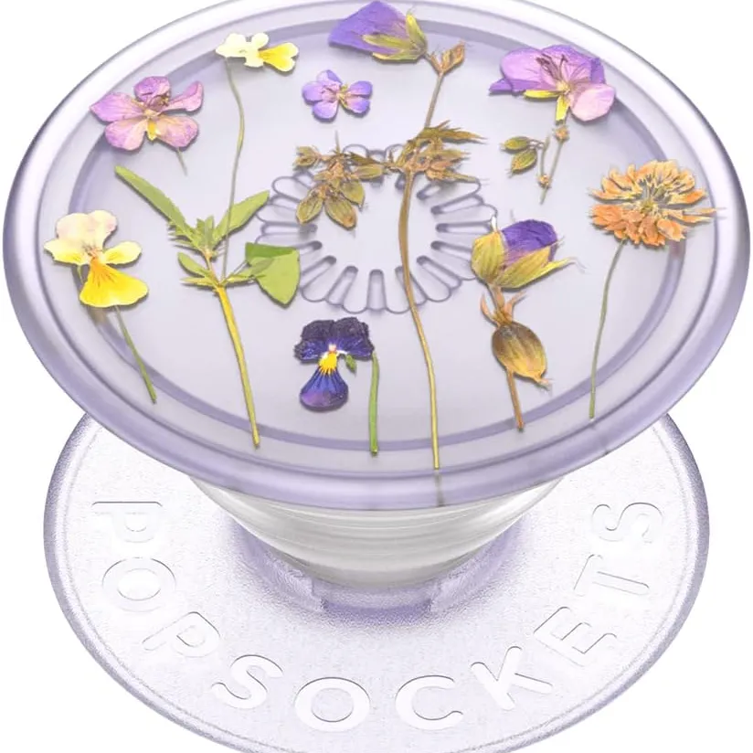 A PopSocket with a clear top featuring a design of pressed flowers, showcasing various colorful blooms on a light purple background.