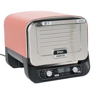 A Ninja Woodfire outdoor grill with digital controls and a salmon-colored lid.
