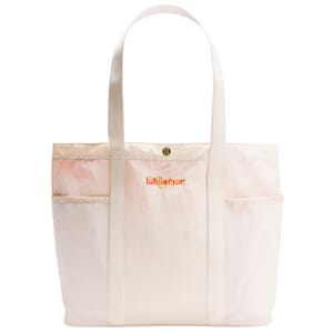 A white lululemon 20L Lunar New Year Tote Bag with orange logo lettering, featuring dual shoulder straps, a snap closure, and two outer pockets for additional storage.