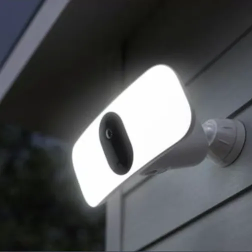 A wall-mounted outdoor security light with a built-in camera, featuring a bright, rectangular LED panel for illumination.