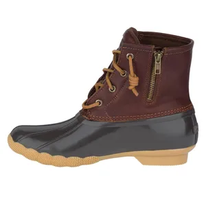 A leather and rubber duck boot with a side zipper and lace-up front, featuring a brown upper, black waterproof lower, and tan rubber sole.