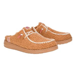 Hey Dude Wendy Sherpa Shoes feature a slip-on mule design with a tan sherpa fabric upper, white stitching, pink accents, and a cushioned, tan rubber outsole, offering comfort and casual style.