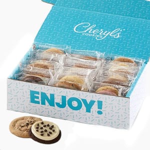 Box of individually wrapped Cheryl's Cookies with a visible \“ENJOY!\“ message on the lid. Two cookies are shown outside, one with chocolate chips and another with icing and chocolate chips.
