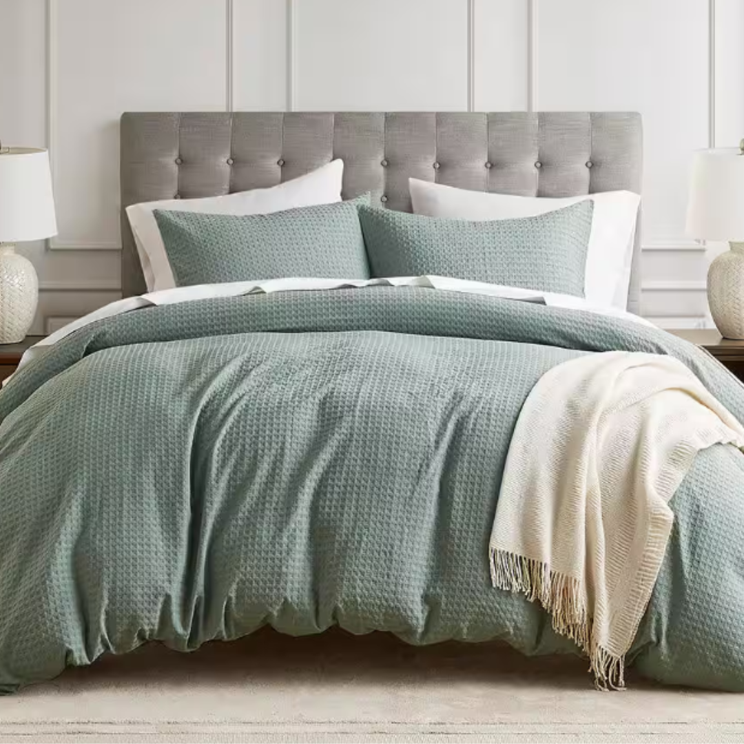 3-piece Queen Duvet Cover Set in a textured waffle knit, featuring a soft blue-green color. It includes a duvet cover and two matching pillow shams, complemented by a neutral white fringed throw blanket.