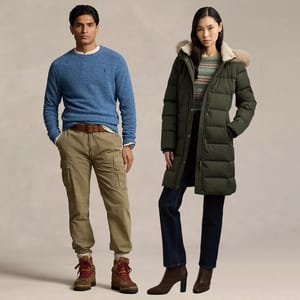 A man is wearing a blue sweater, khaki cargo pants, and brown boots, while a woman is dressed in a green puffer coat with a fur-trimmed hood, patterned sweater, dark jeans, and brown heeled boots.
