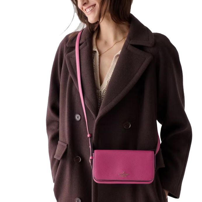 A woman wearing a dark brown coat holds a bright pink crossbody bag.