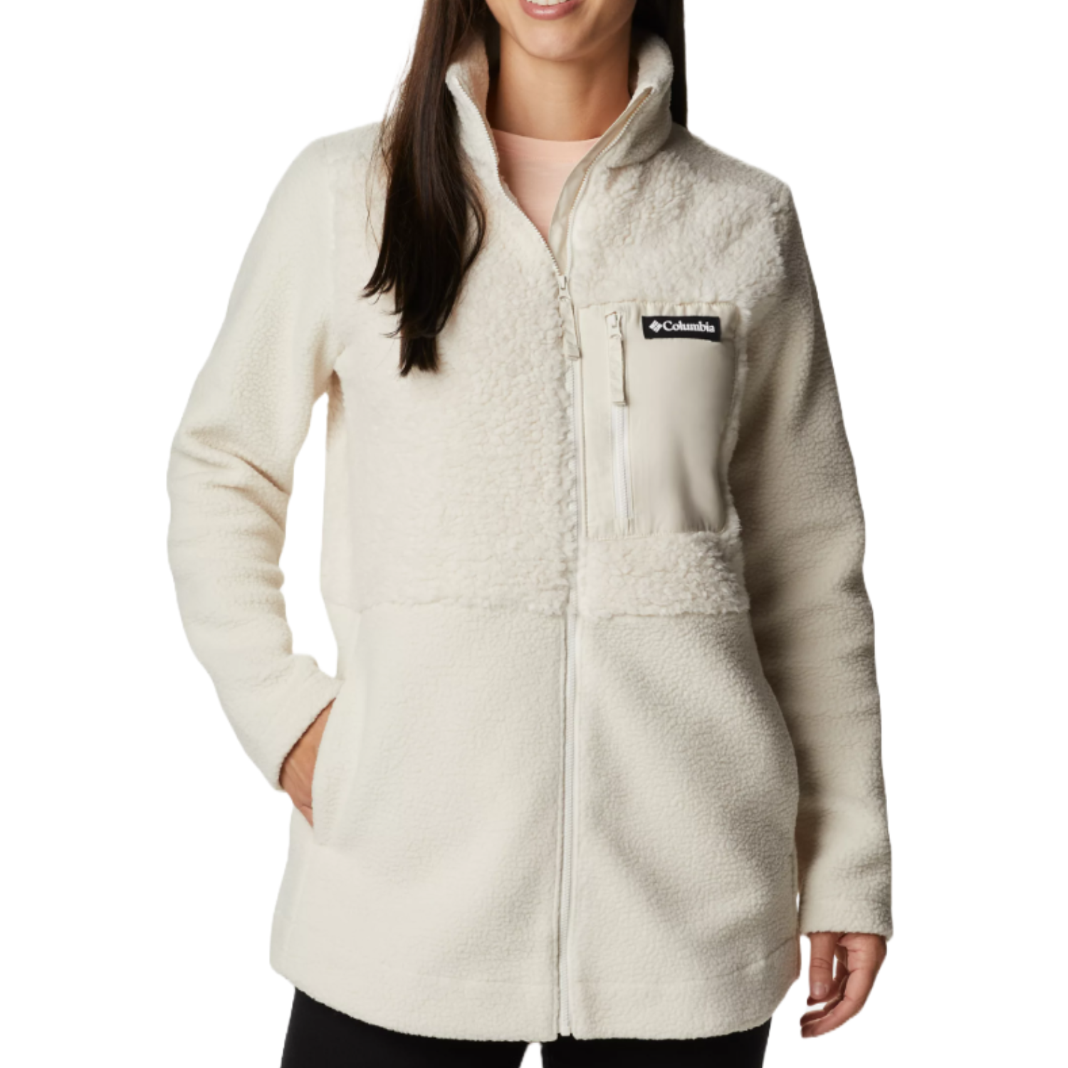 A woman is wearing a cream-colored Columbia fleece jacket with a high collar and a chest pocket featuring the Columbia logo.