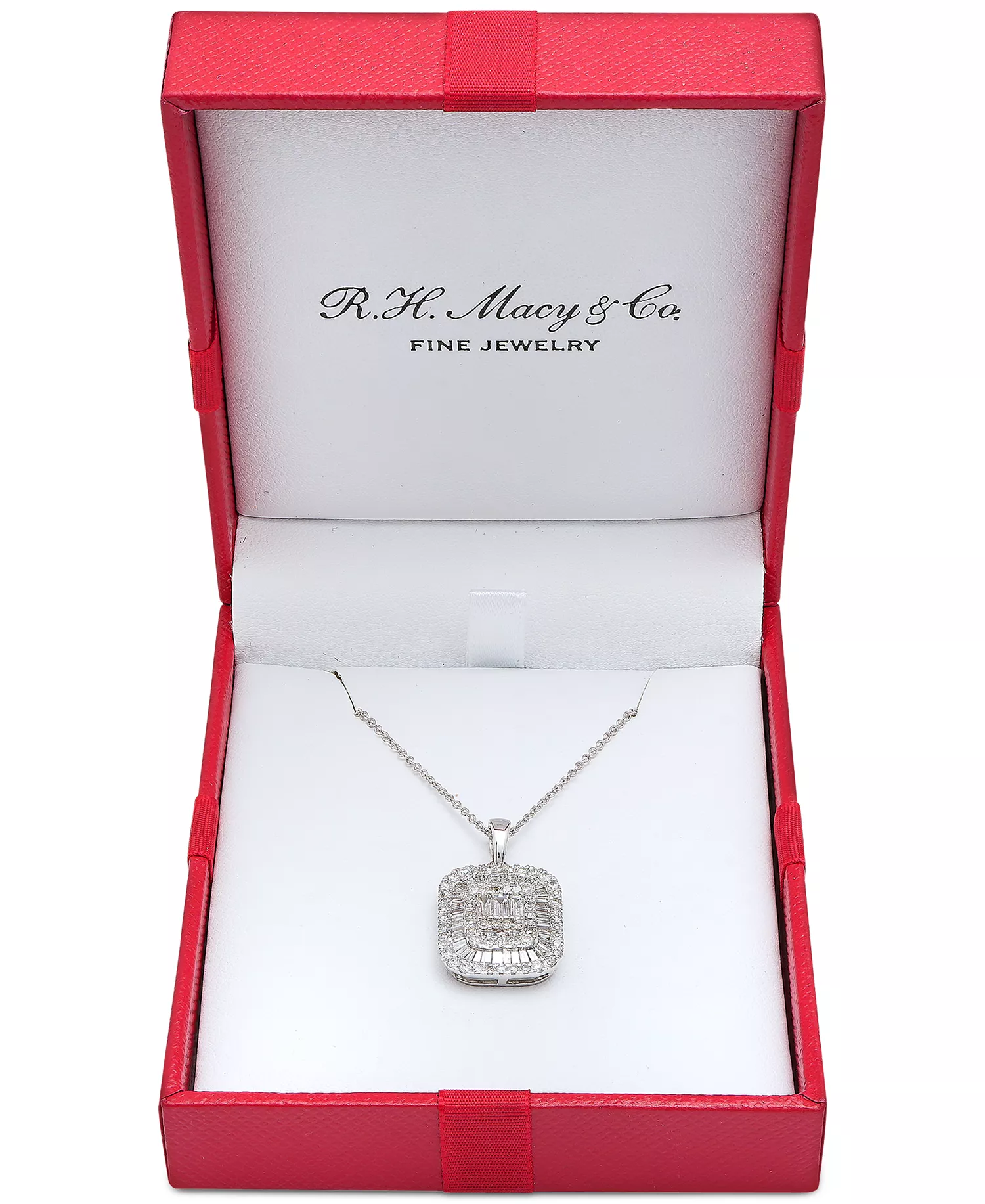 A silver necklace with a rectangular pendant featuring intricate diamond detailing is displayed in an open red jewelry box labeled \“R.H. Macy & Co. Fine Jewelry.\“