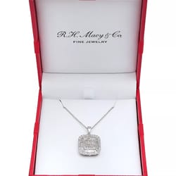 A silver necklace with a rectangular pendant featuring intricate diamond detailing is displayed in an open red jewelry box labeled \“R.H. Macy & Co. Fine Jewelry.\“