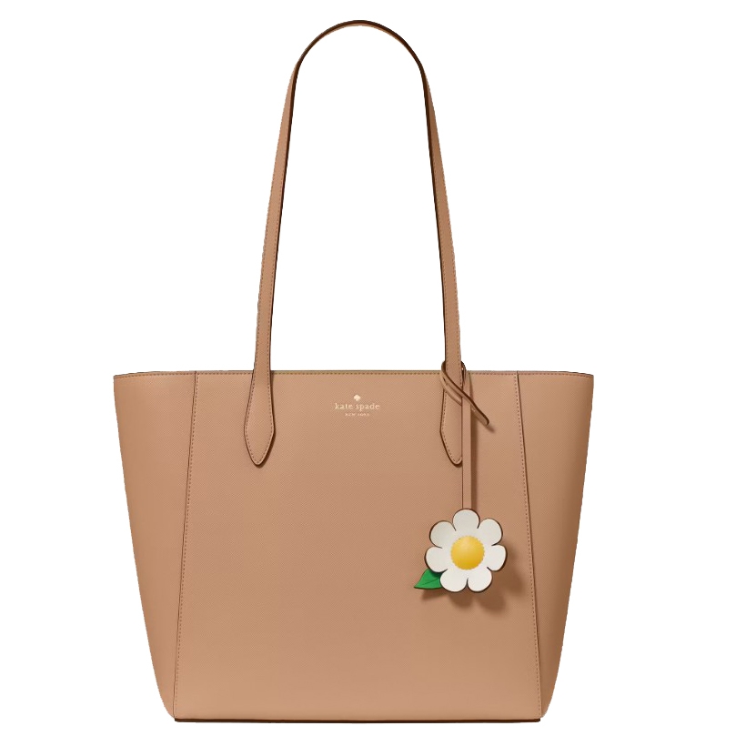 A beige tote bag with two long handles, featuring a floral charm and the \“kate spade new york\“ logo.