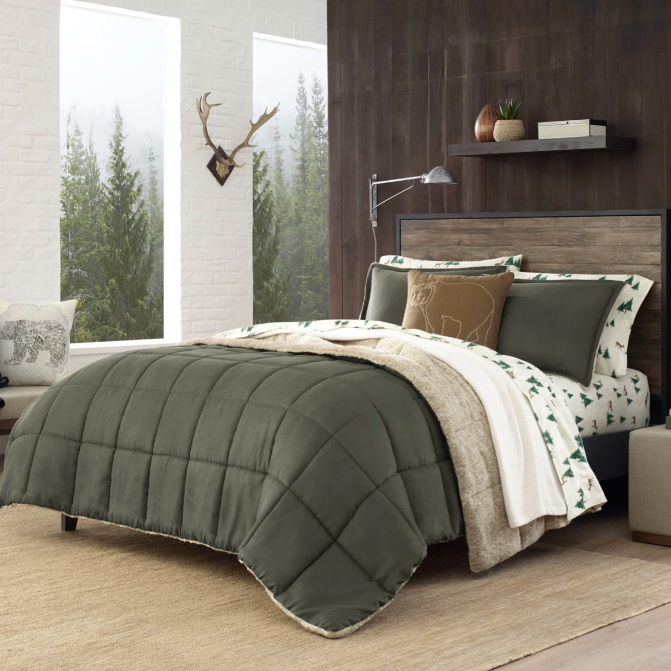 Bedroom with pine green quilted comforter, beige and green tree-patterned sheets, and a decorative bear pillow. The setting features a wooden headboard, wall shelf with plants, and a window with a forest view. A beige rug covers the floor.