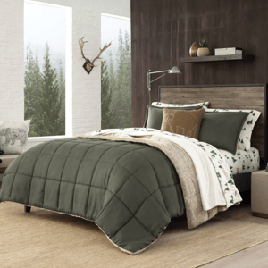 Bedroom with pine green quilted comforter, beige and green tree-patterned sheets, and a decorative bear pillow. The setting features a wooden headboard, wall shelf with plants, and a window with a forest view. A beige rug covers the floor.