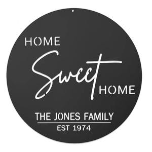 A round black sign reading \“Home Sweet Home\“ with \“The Jones Family\“ and \“Est 1974\“ in white text.