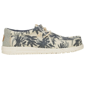 Canvas slip-on shoe with a tropical leaf pattern, featuring a speckled white sole and beige laces.